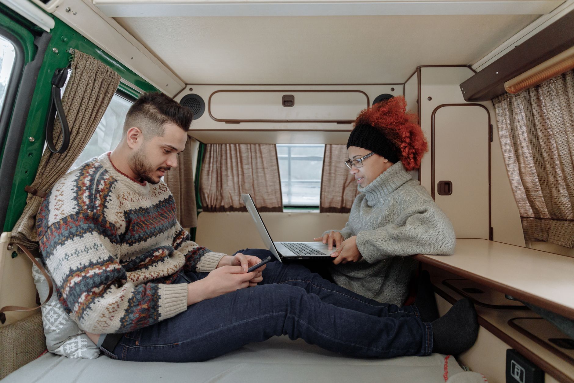 Person holding smartphone showing battery monitoring app next to RV battery