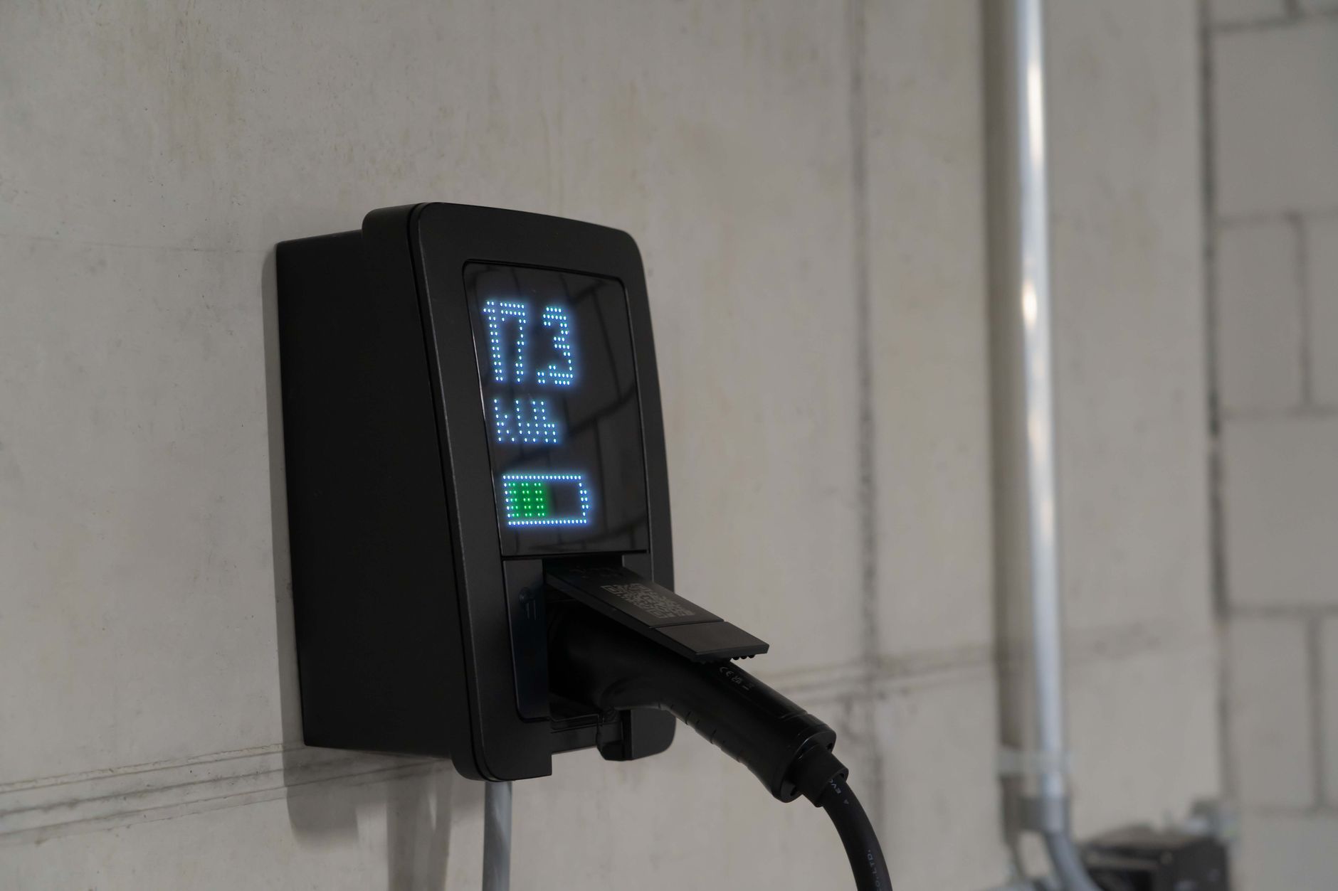 White Tesla Powerwall battery mounted on a garage wall next to an electrical panel