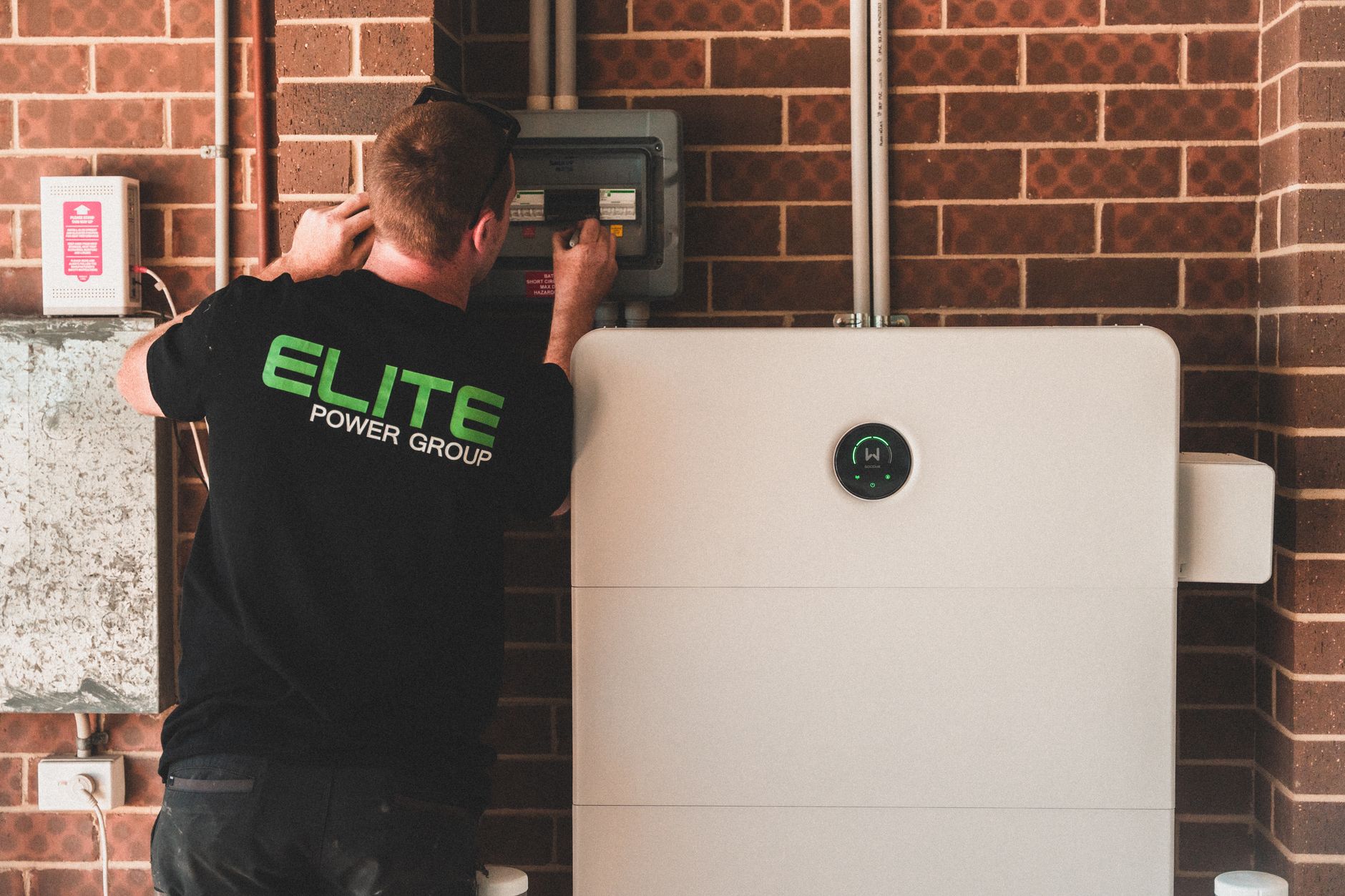 A technician wiring a hybrid solar inverter and wall-mounted battery storage unit
