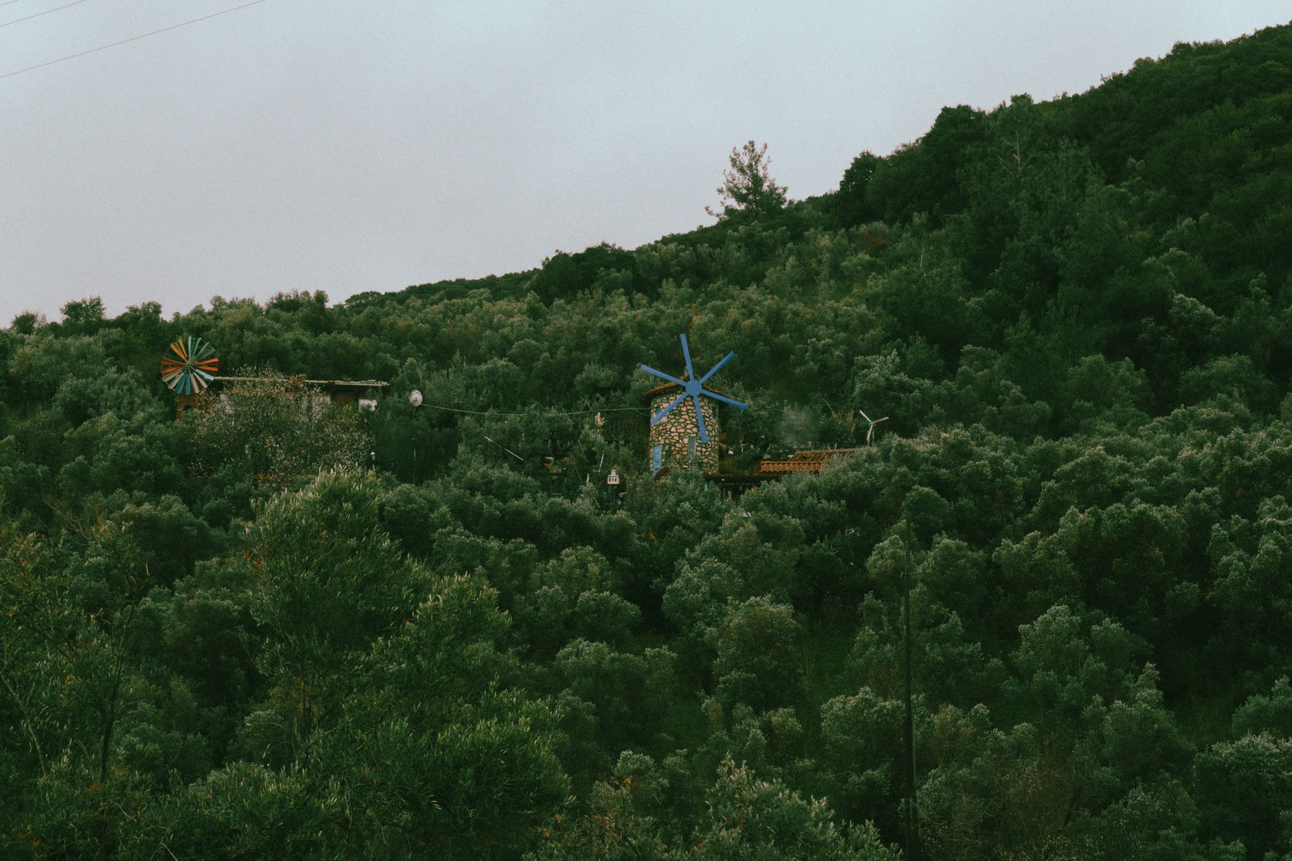 Small micro wind turbine mounted on a pole next to a wooden off-grid cabin